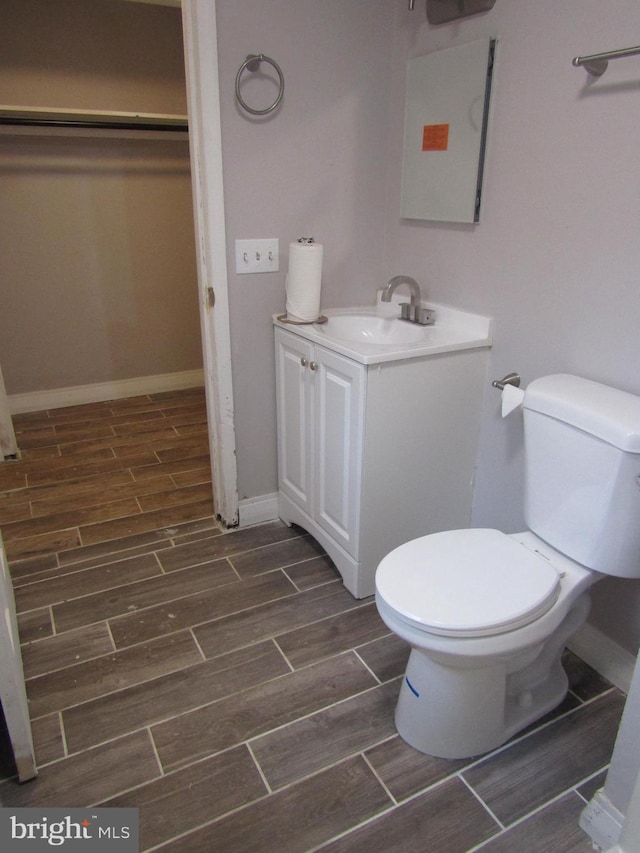 bathroom featuring wood tiled floor, baseboards, vanity, and toilet