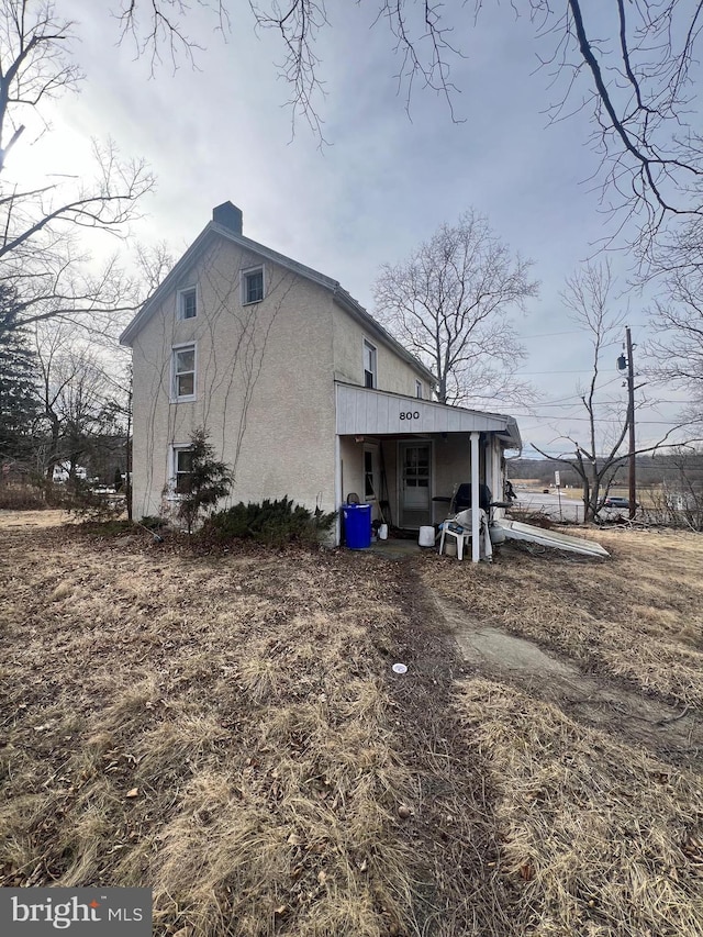 view of side of property featuring a chimney and stucco siding