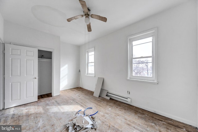 unfurnished bedroom featuring ceiling fan, light hardwood / wood-style flooring, a closet, and a baseboard heating unit