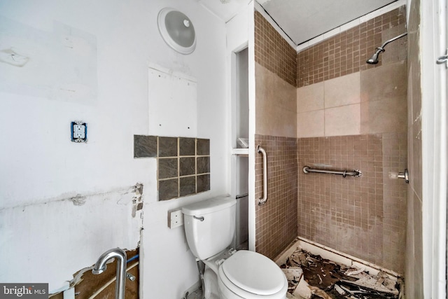 bathroom with a tile shower and toilet