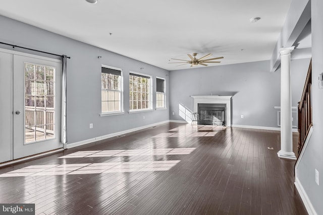 unfurnished living room featuring ornate columns, wood-type flooring, ceiling fan, and a glass covered fireplace