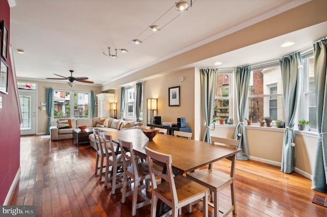 dining space with a ceiling fan, wood-type flooring, crown molding, and baseboards