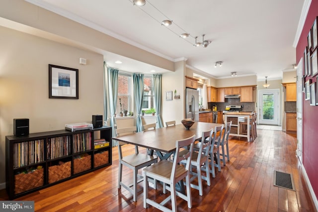 dining room with wood-type flooring, visible vents, and crown molding