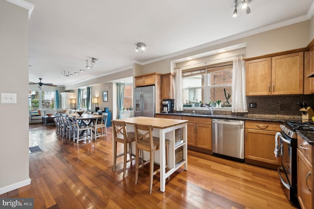 kitchen featuring appliances with stainless steel finishes, dark countertops, hardwood / wood-style floors, and decorative backsplash