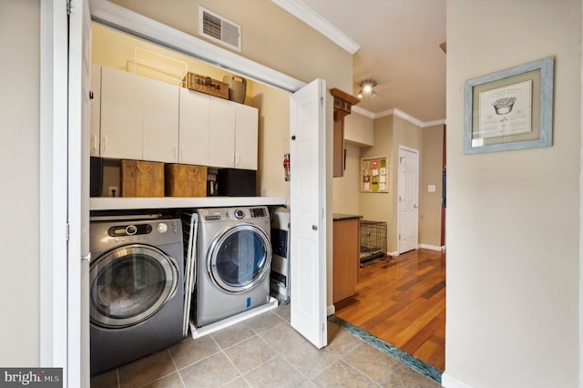 laundry room featuring tile patterned flooring, visible vents, cabinet space, washing machine and clothes dryer, and crown molding