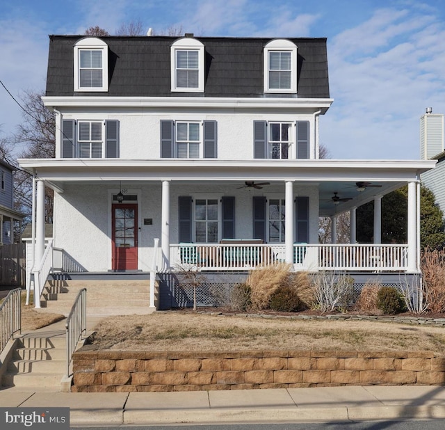 view of front of house featuring a porch, a ceiling fan, stucco siding, and mansard roof