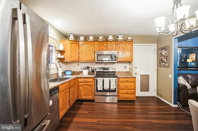 kitchen featuring appliances with stainless steel finishes, a notable chandelier, decorative light fixtures, dark hardwood / wood-style flooring, and sink