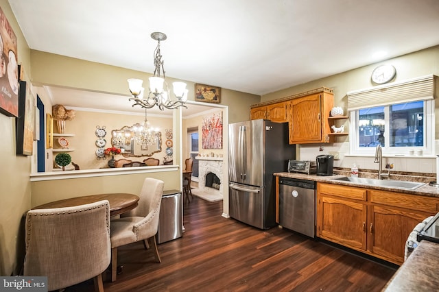 kitchen featuring hanging light fixtures, dark wood-type flooring, stainless steel appliances, a chandelier, and sink