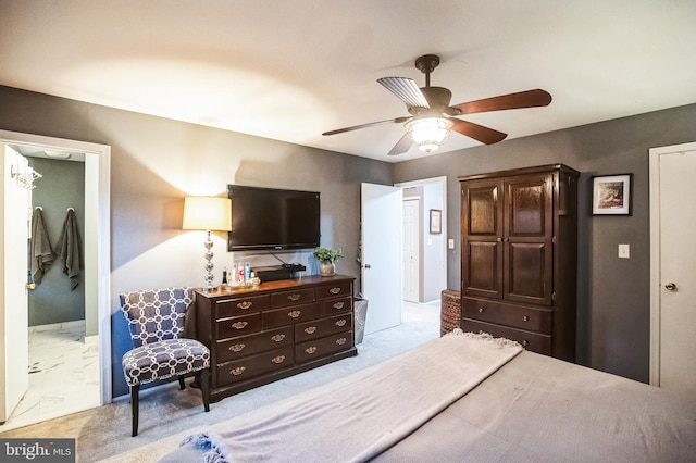 carpeted bedroom with ensuite bathroom and ceiling fan