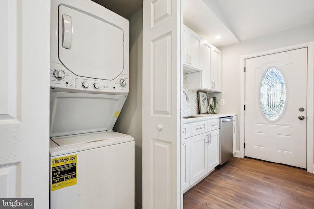 laundry area with sink, stacked washing maching and dryer, and light hardwood / wood-style flooring