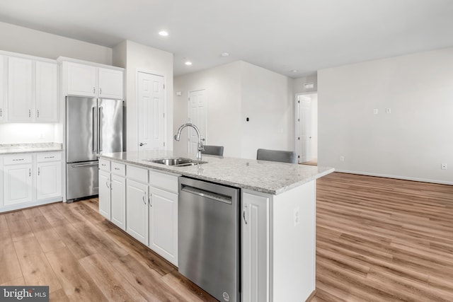 kitchen featuring an island with sink, stainless steel appliances, light hardwood / wood-style flooring, sink, and white cabinets