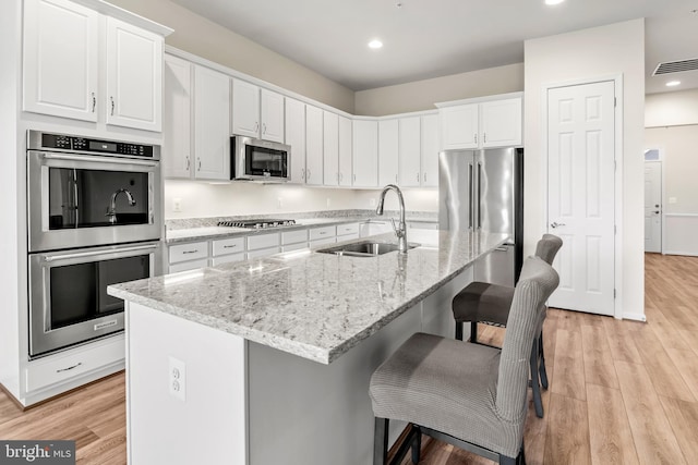 kitchen featuring appliances with stainless steel finishes, a kitchen island with sink, and white cabinets