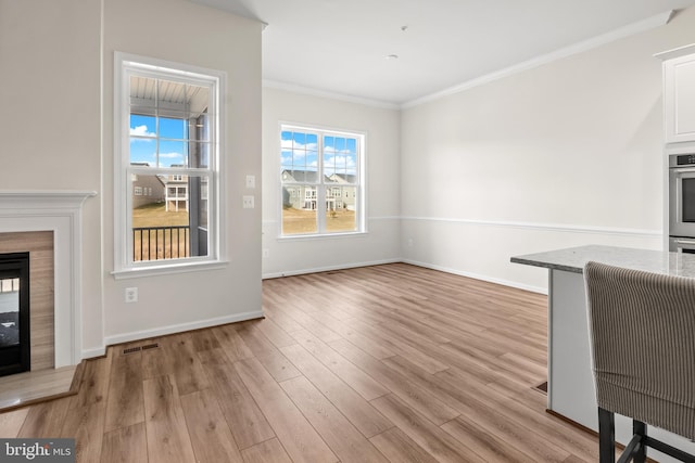 unfurnished living room with light wood-type flooring and crown molding