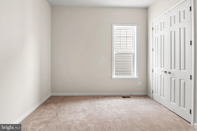 unfurnished bedroom featuring a closet and light colored carpet