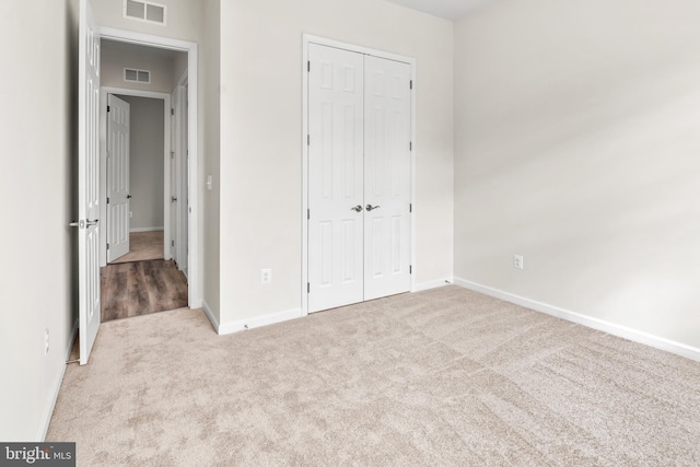 unfurnished bedroom with a closet and light colored carpet