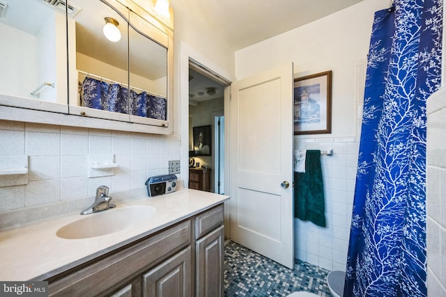 full bath with a wainscoted wall, tile walls, curtained shower, visible vents, and vanity