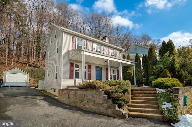 front of property featuring covered porch, an outdoor structure, and a garage