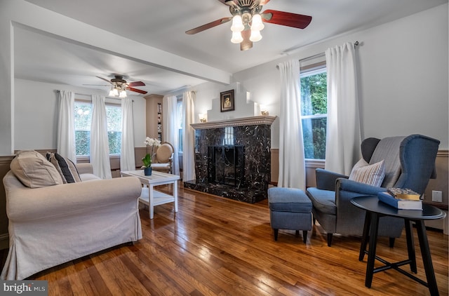 living room with a fireplace, hardwood / wood-style floors, beamed ceiling, and ceiling fan