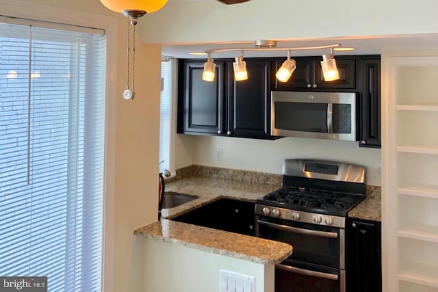 kitchen featuring appliances with stainless steel finishes, decorative light fixtures, sink, and light stone countertops