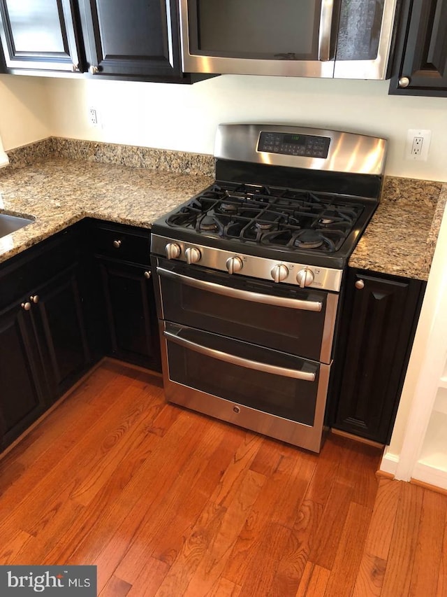 kitchen featuring light hardwood / wood-style floors, appliances with stainless steel finishes, and light stone counters