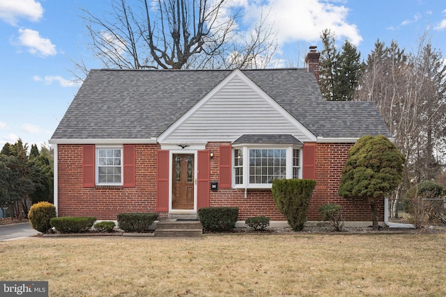 view of front of house with a chimney, a front lawn, and brick siding