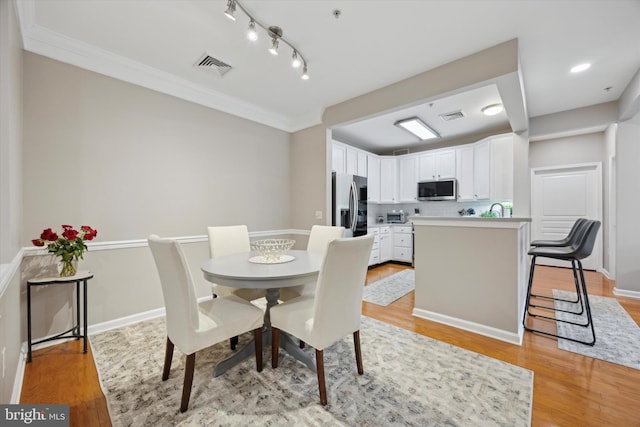 dining room featuring light wood finished floors, visible vents, and baseboards