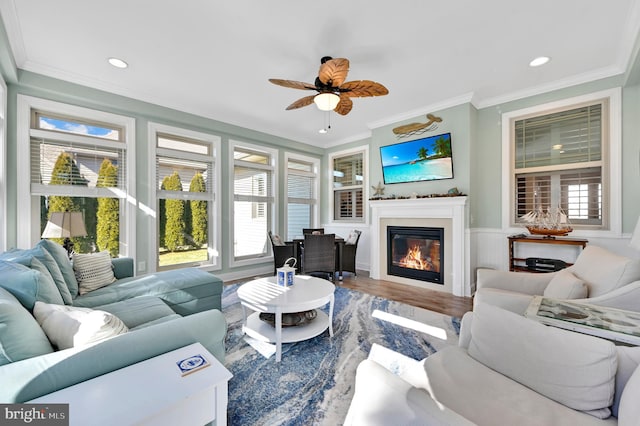 living room with hardwood / wood-style flooring, ceiling fan, crown molding, and a healthy amount of sunlight