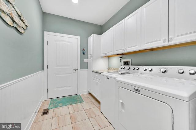 laundry area featuring washing machine and dryer, cabinets, and light tile patterned floors