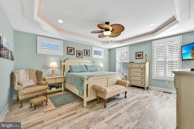 bedroom featuring a tray ceiling, ceiling fan, and light hardwood / wood-style floors