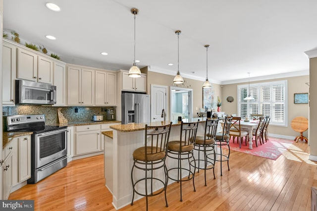 kitchen featuring a center island with sink, tasteful backsplash, a kitchen breakfast bar, stainless steel appliances, and pendant lighting