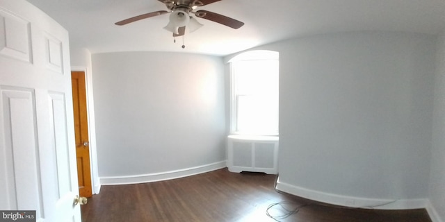 empty room with ceiling fan, dark wood-type flooring, and radiator heating unit