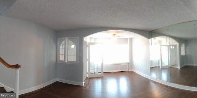 unfurnished dining area featuring a textured ceiling and dark wood-type flooring