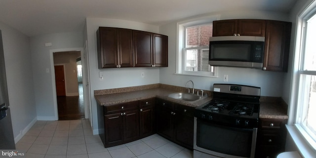 kitchen featuring appliances with stainless steel finishes, light tile patterned flooring, sink, and dark brown cabinetry