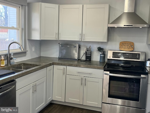 kitchen featuring a sink, white cabinets, wall chimney range hood, dark countertops, and stainless steel range with electric stovetop