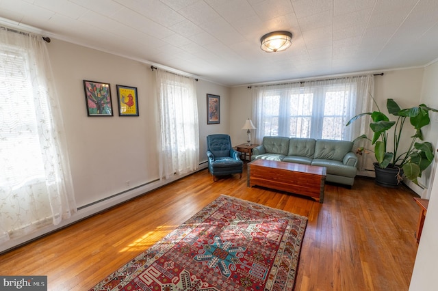 living area with a healthy amount of sunlight, crown molding, baseboard heating, and wood finished floors