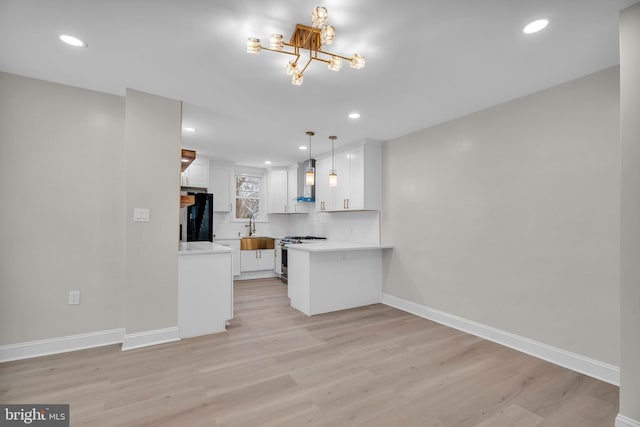 kitchen featuring decorative light fixtures, stainless steel stove, light countertops, white cabinets, and black fridge