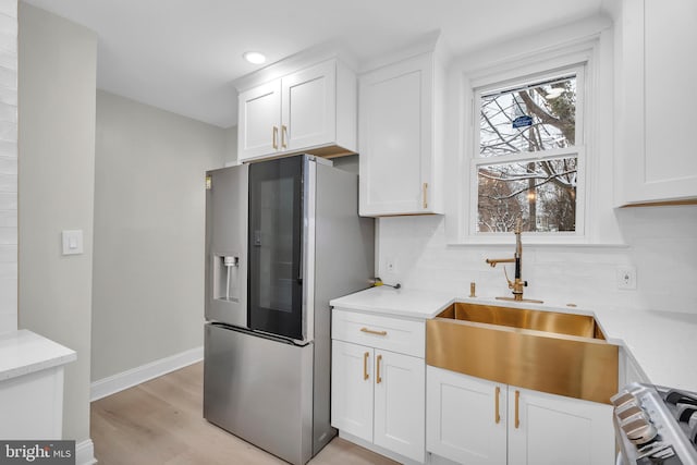 kitchen with white cabinets, a sink, stainless steel appliances, and light countertops