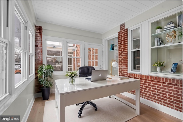 office area featuring baseboards, light wood-style flooring, and brick wall