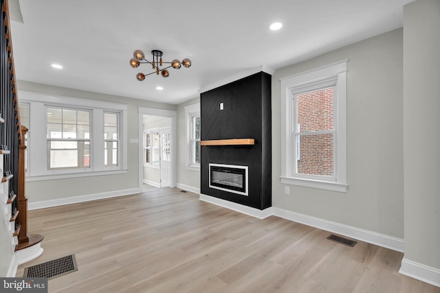 unfurnished living room with light wood-type flooring, a fireplace, visible vents, and baseboards