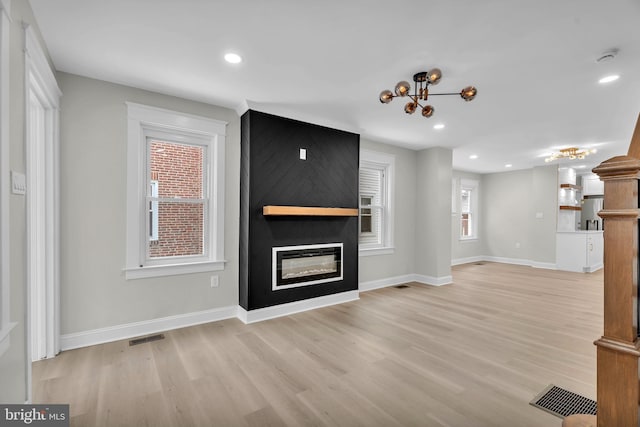 unfurnished living room with a large fireplace, visible vents, and light wood finished floors