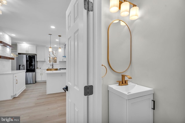 bathroom with a sink, two vanities, wood finished floors, and recessed lighting