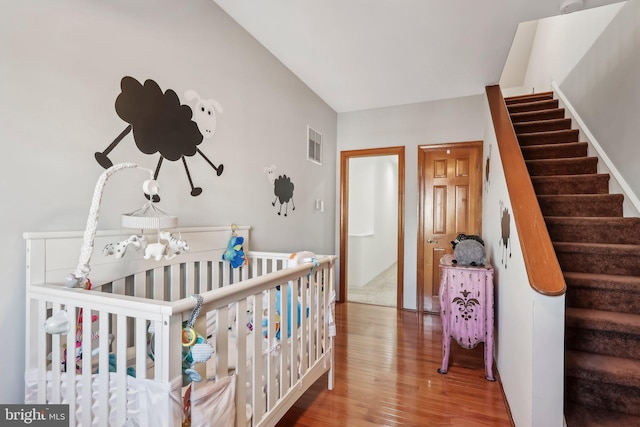 bedroom with a crib and wood-type flooring