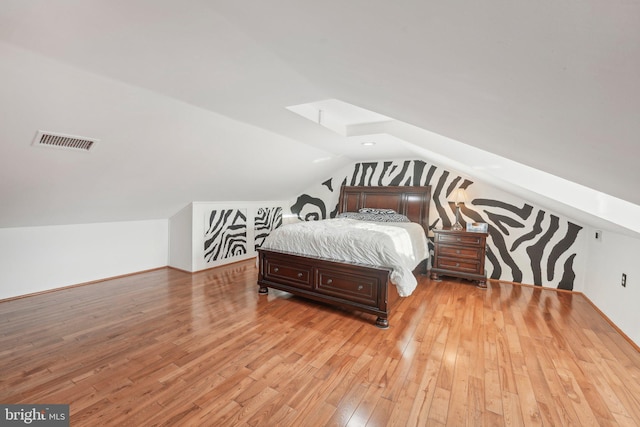 bedroom with vaulted ceiling and light hardwood / wood-style flooring