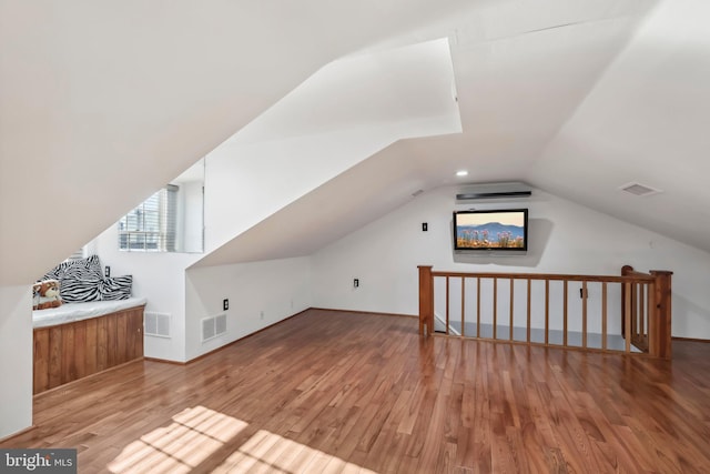 additional living space featuring vaulted ceiling and light hardwood / wood-style flooring