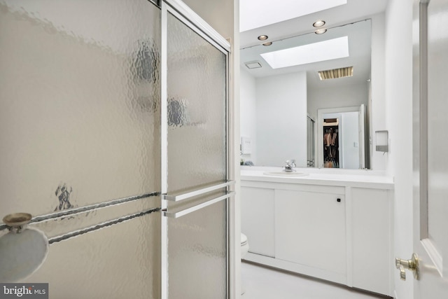 bathroom featuring a shower with shower door, vanity, toilet, and a skylight