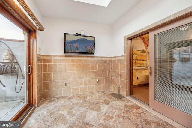 bathroom featuring tile walls and a skylight