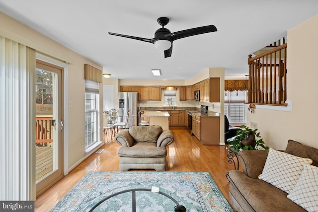 living area featuring light wood-style flooring, ceiling fan, and a wealth of natural light