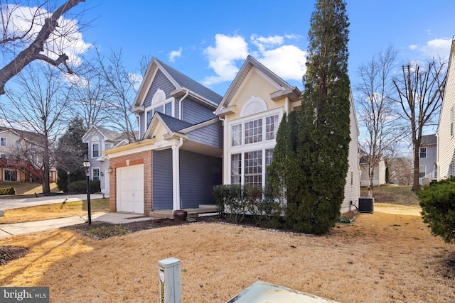 traditional-style house with a garage, driveway, brick siding, and central AC unit