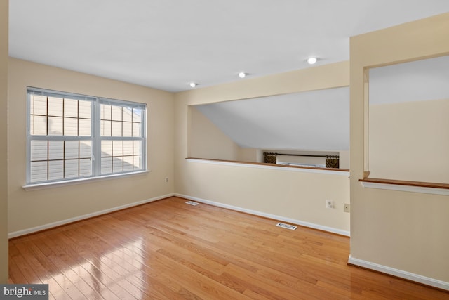 empty room featuring wood-type flooring, visible vents, and baseboards