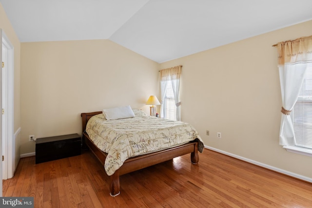 bedroom with lofted ceiling, baseboards, and wood finished floors